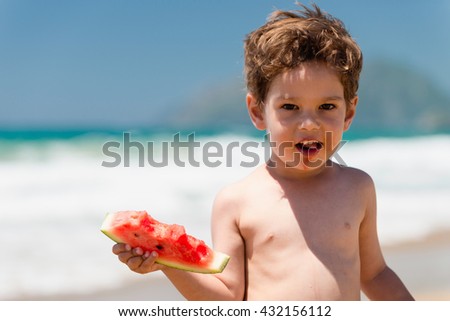 Cute little boy eating watermelon on the beach