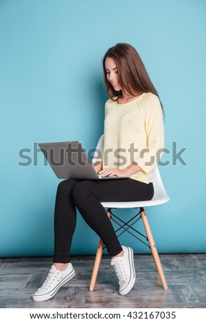 Young beautiful smart girl using laptop pc computer for study isolated on the blue background