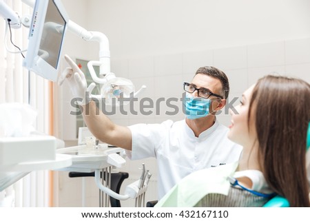Dentist explaining x ray picture to patient on led monitor in clinic