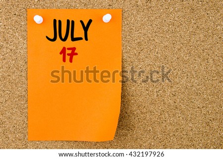 17 JULY written on orange paper note pinned on cork board with white thumbtacks, copy space available