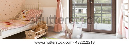 Child room for a girl in pastel shades and glass doors to the balcony