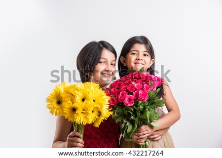 Two Cute Little Indian Girls holding a bunch / bouquet of Fresh Red Roses or Gulab flowers. Isolated over white background