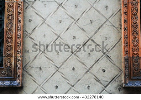 The gray plastered wall with geometric designs. Window frame of red ceramic tile reliefs.