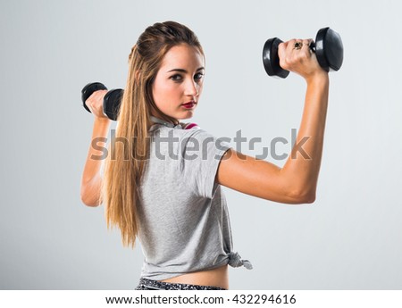 Young woman doing weightlifting over grey background