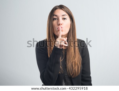 Girl making silence gesture over grey background