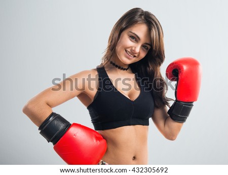 Young girl with boxing gloves over grey background