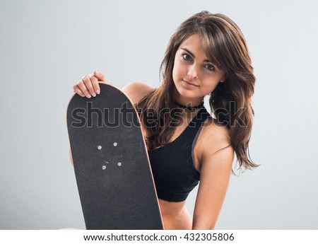Young girl with skateboard over grey background