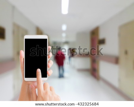woman use mobile phone and blurred image of a man walk on the corridor of hospital
