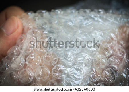 hands popping the bubbles in bubble wrap on black background (selective focus) Royalty-Free Stock Photo #432340633