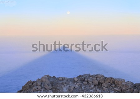 Landscape with stones, shadow of  Teide and moon in sunrise light. Tenerife, Canary islands, Spain