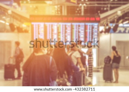 blurred of Traveler at airport terminal with flight schedule board.