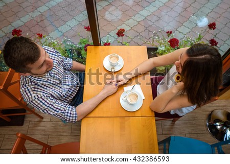 Man holds woman's hand with cup of coffee top view image on wooden backdrop