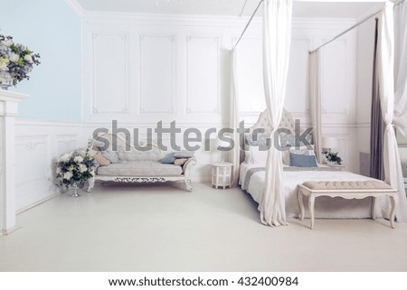 bright, clean stylish interior bedroom and living room with a large panoramic window. beautiful rich antique furniture. four-poster bed, a mirror and a sofa.
