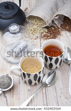 two cups 1 black tea rooibos and other fennel with teapot in the