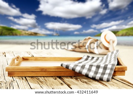 slim woman in bikini on hot sand and sea landscape with blue napkin on wooden tray 