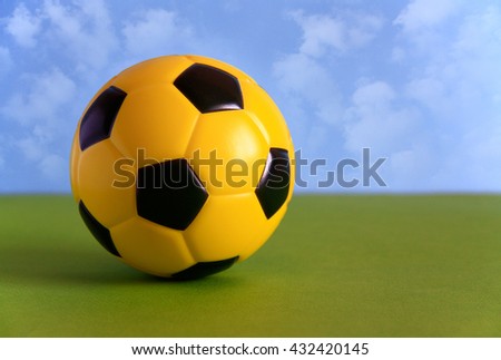 Yellow - black soccer ball on the green field against the blue sky