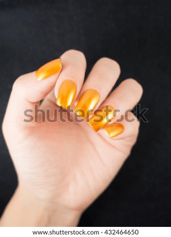Close up of female hands showing colorful nail polish. The woman is wearing golden manicure.