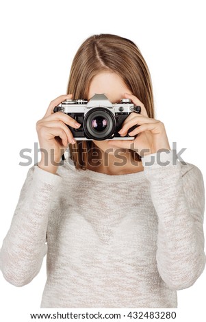 young woman holding vintage camera while pressing the shutter button. image on a wight studio background.
