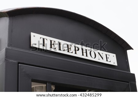 Vintage big black pay phone on white sky.