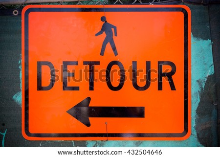 An orange detour sign with a arrow and a pedestrian 