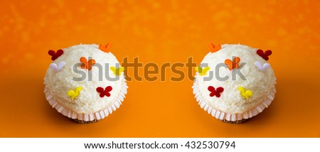 white cupcakes on orange background panorama
