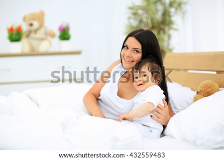 mother and baby in diaper playing in sunny bedroom