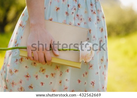 Close-up of female hands holding book in spring park. Reading concept background
