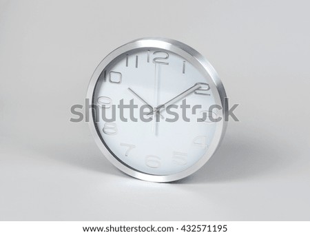 Stainless steel and white wall clock stands on gray background - silver or chrome clock