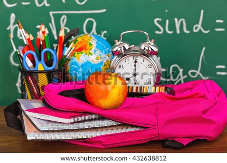 Back to school - blackboard with pencil-box and school equipment on table 
