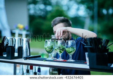 Barman making mojito cocktail and pours alcohol into the glass outdoor Royalty-Free Stock Photo #432676405