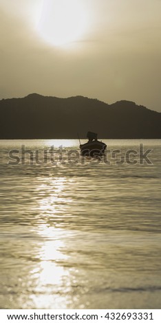 traditional boat laying on peace wave surface of the sea, big mountain and sunrise/sunset in background , Vertical picture ,Prachuapkhirikhan Thailand