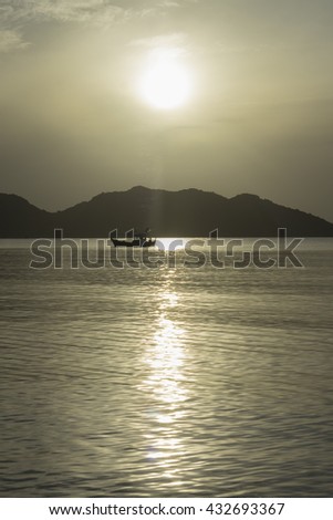 traditional boat laying on peace wave surface of the sea, big mountain and sunrise/sunset in background , Vertical picture ,Prachuapkhirikhan Thailand