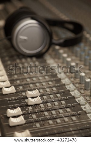 two faders of old dirty sound mixer in focus. headphones in out of focus