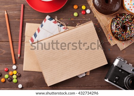 Notepad, donuts and coffee on wooden table. Top view with copy space