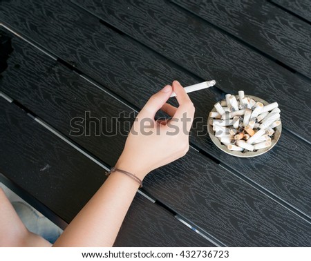 in hand have cigarette , full  Ashtray close