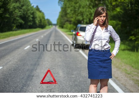 Young woman standing on the road after breakdown and calling to a car assistance.