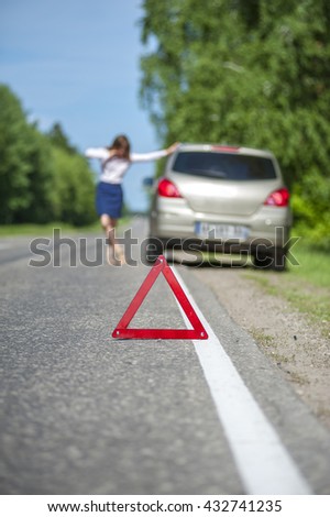 Red triangle warning sign and woman calling for assistance after breakdown. Selective focus
