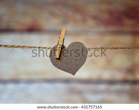 Love heart hanging on rope on a blurred wooden background