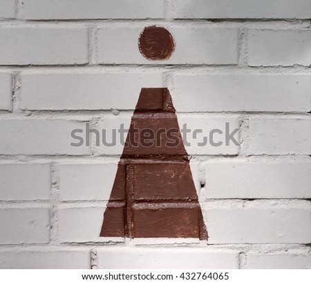 Brown vintage woman sign painted on the beige brick wall next to the public toilet entrance