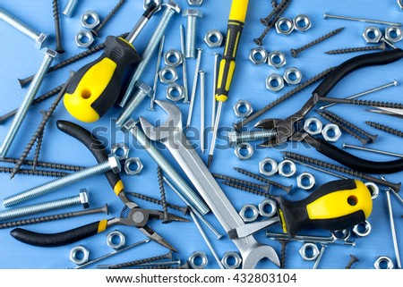 working tools near the bolts to screws and nails and screws scattered on a blue background