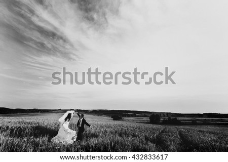 A black and white picture of bride and fiance dancing on the field