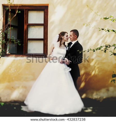 Wedding couple poses in the front of old wooden window