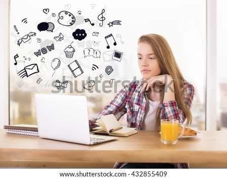 Social media and online communication concept with young woman using laptop with creative sketches on wooden desktop 