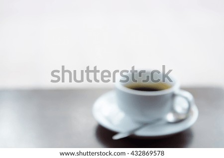 Defocused and blurred image of hot coffee in white cup  on wooden table use for the background