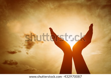 Raised hands catching sun on sunset sky. Concept of spirituality, wellbeing, positive energy etc. Royalty-Free Stock Photo #432970087