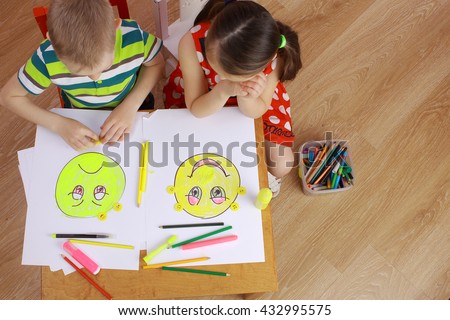 the development of emotional intelligence. child psychology. girl and boy depict different emotions. the girl and the boy draw happy and sad emoticons Royalty-Free Stock Photo #432995575