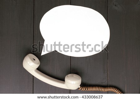 handset lying on a wooden table and departing from it idea talking / sound from telephone handset