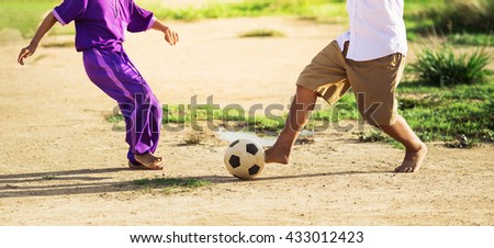 An action picture of the boys are playing soccer football in the sunshine day. Focus on the legs and ball.