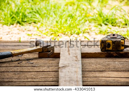 Background Craftsman tool with old hammer with tape measure and small nails on wooden background and outdoor view.Background for carpenter and repair and craft country style.