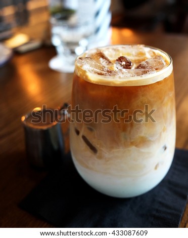Iced latte served in the glass on wooden table at restaurant (Low-key Picture Style)